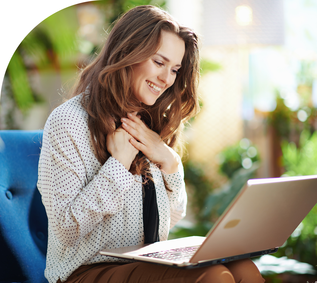 Woman smiling at laptop in cozy setting.